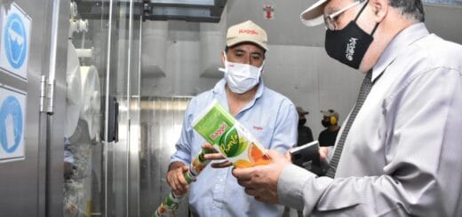 alt="el intendente Francolini observa un envase con jugos cítricos que le ofrece un operario"