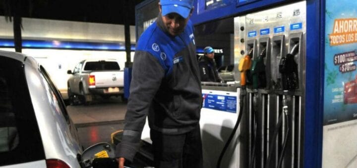 alt="empleado de una estación de servicio carga combustible a un auto"