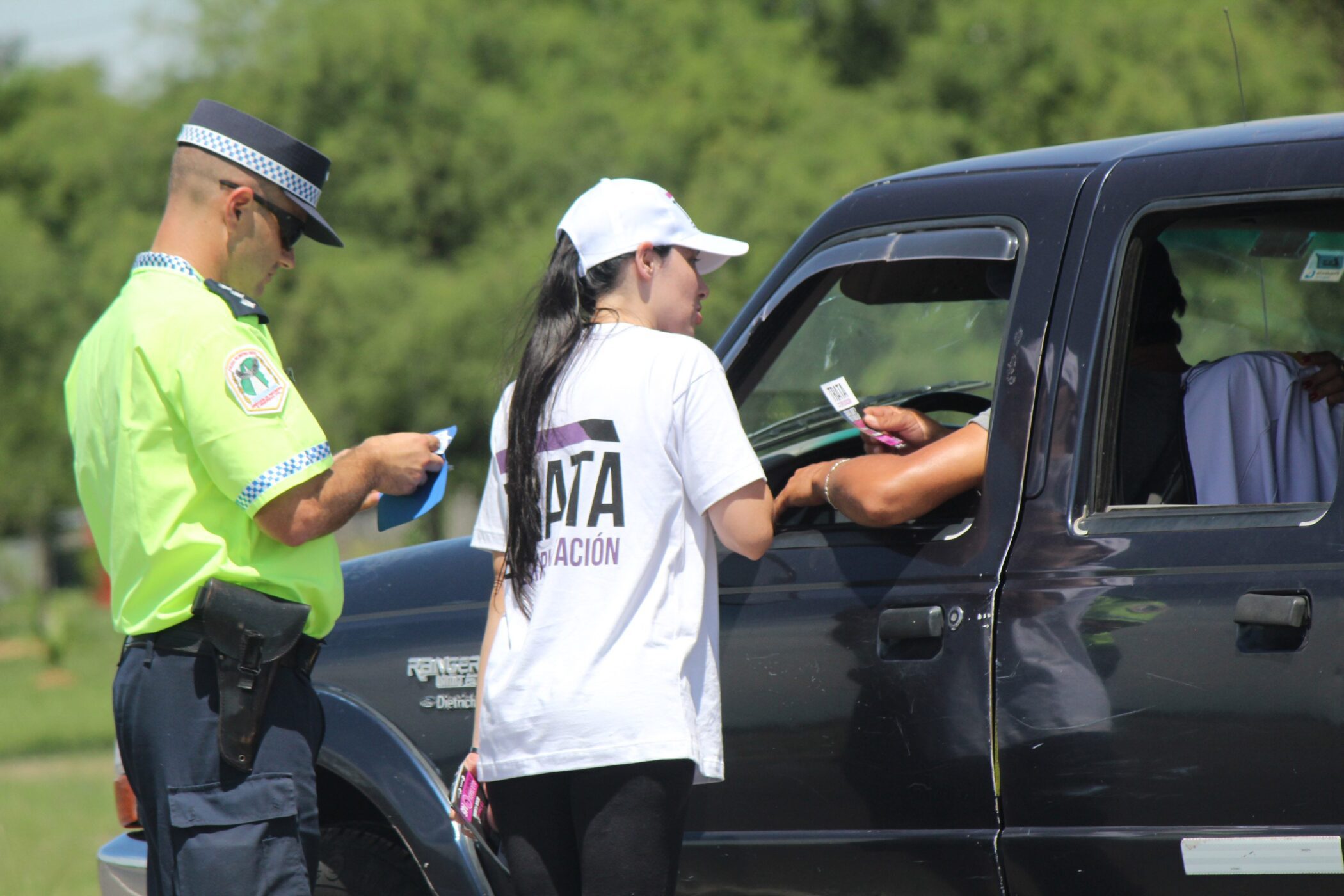 alt="policía en un puesto caminero controlando documentación a un conductor junto a una funcionaria de transporte"