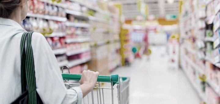 alt="cliente con carrito recorre las góndolas de un supermercado"