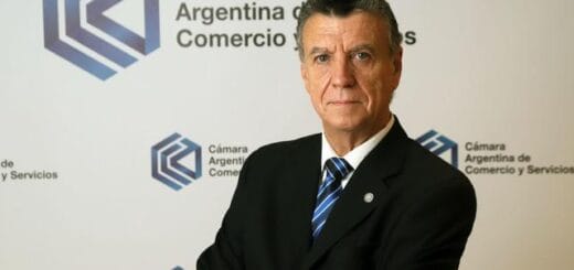 alt="natalio mario grinman posa ante un cartel de la cámara argentina de comercio y servicios"