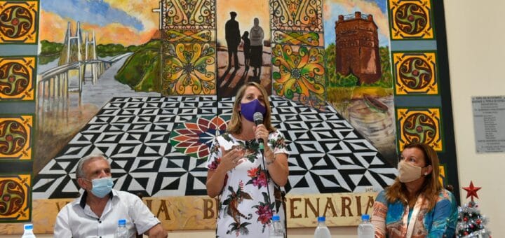 alt="vicegobernadora hablando y dos personas sentadas en una mesa"