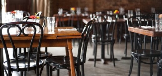 alt="mesas y sillas en el interior de un restaurante sin comensales"