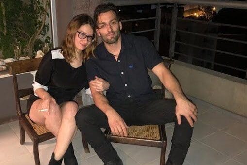 alt="julieta riera y jorge julián christe sentados cerca de un balcón"