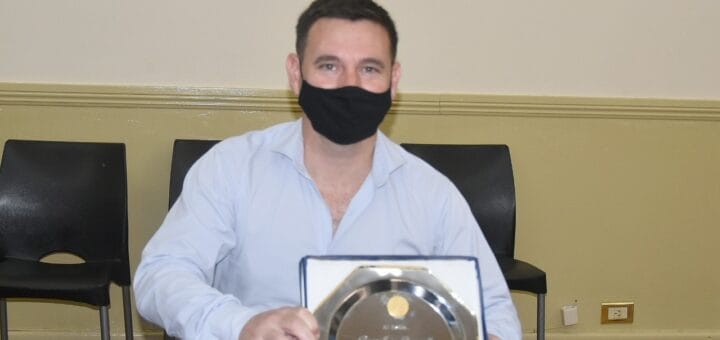 alt="diego pasarello exhibe un reconocimiento entregado por su gestión en la municipalidad de Concordia"
