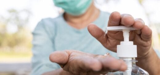 alt="persona con barbijo se pone alcohol en gel en sus manos"