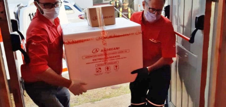 alt="dos hombres cargan un contenedor con vacunas Sputnik V"