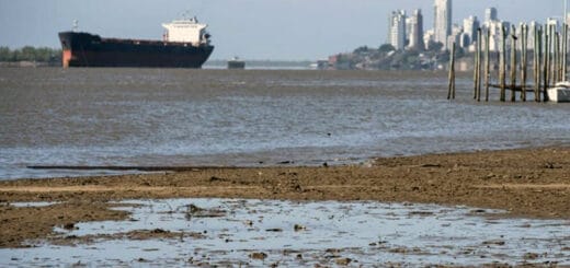 alt="barco navegando, detrás un puerto e infraestructura para exportar cereales"