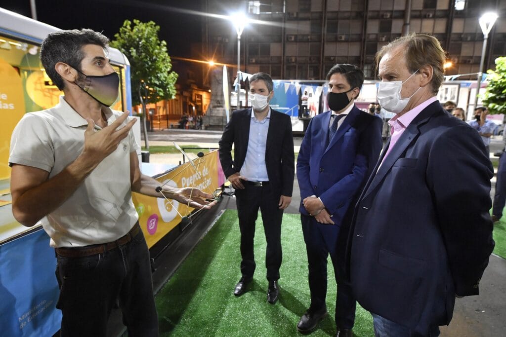 alt="el gobernador Bordet, el ministro Trota y Martín Muller dialogan con un hombre en plaza Alsina"