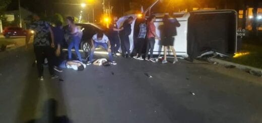 alt="dos personas heridas tendidas sobre el pavimento, otras cuatro tratan de ayudarla y cinco sostienen una camioneta volcada"