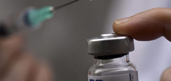 alt="aguja de una jeringa y recipiente de una vacuna"