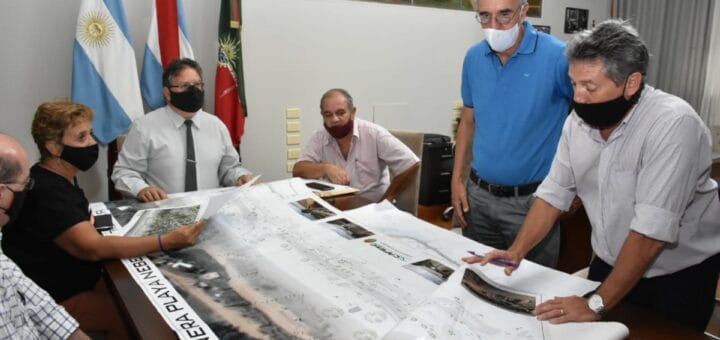 alt="se ve a seis personas que examinan el plano proyectado de la nueva costanera nébel"