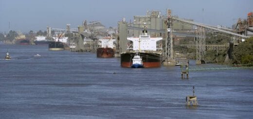 alt="tres barcos recibiendo carga en un puerto cerealero"