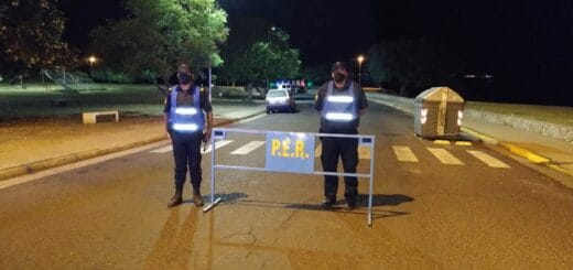 alt="dos policías frente a una valla que atraviesa una calle"