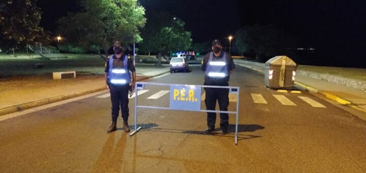 alt="dos policías frente a una valla que atraviesa una calle"