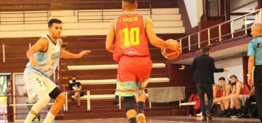 alt="un jugador de tomás de rocamora avanza haciendo picar la pelota ante otro de racing de chivilcoy"