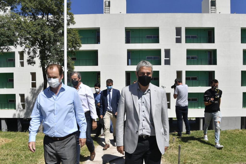 alt="en primer plano el gobernador bordet y el ministro ferraresi, detrás el intendente de Paraná y funcionarios, al fondo viviendas de departamentos"