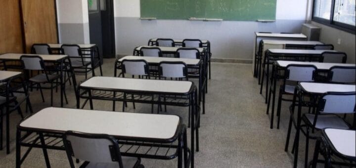 alt="un aula con el pizarrón y los bancos, sin alumnos y sin docentes"