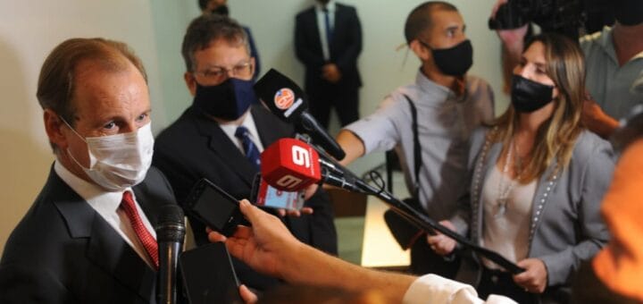 alt="en primer plano, el gobernador realiza declaraciones ante micrófonos de medios de comuniación; detrás el intendente de Concordia"