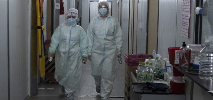 alt="dos personas pertenecientes a un equipo de salud caminan por un pasillo"