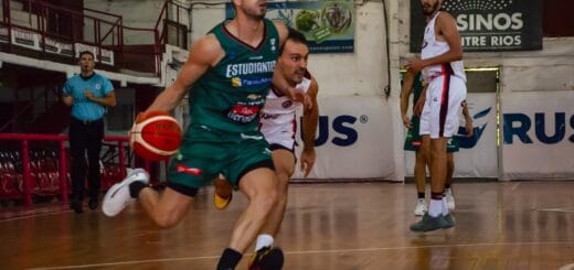 alt="un jugador de básquet corre con la pelota y es perseguido por otro, un tercero los mira"