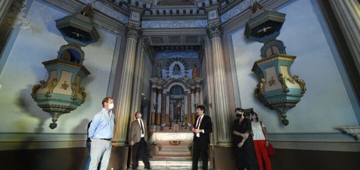 alt="el ministro bauer y el gobernador bordet con otras tres personas en el interior de capilla del palacio de san josé, entre dos púlpitos, al fondo un altar"