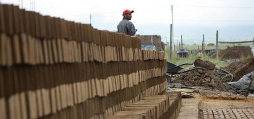 alt="trabajador ladrillero junto a una pila de ladrillos"