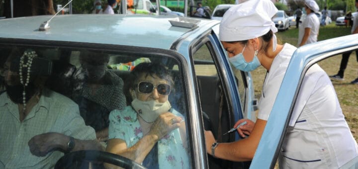 alt="adulta mayor recibe vacuna arriba del auto"