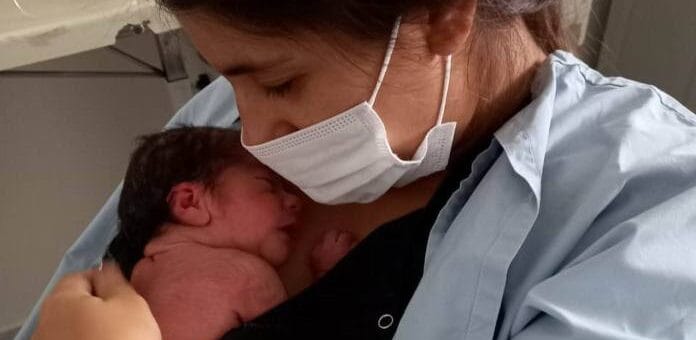 alt="bebé recién nacido con su madre que tiene puesto un barbijo"