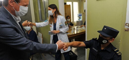 alt="el gobernador saluda con el puño a un policía, en segundo plano una médica hace lo mismo con otra persona"