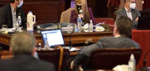 alt="la ministra Sonia Velazquez, de frente, flanqueda a la derecha por el presidente de la cámara de diputados y a la izquierda por otra persona, dos personas de espaldas en la fotografía, la escuchan"