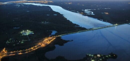 alt="en la fotografía se observa el lago y la represa de Salto Grande y el río Uruguay, también las luces de la ciudad de Concordia"