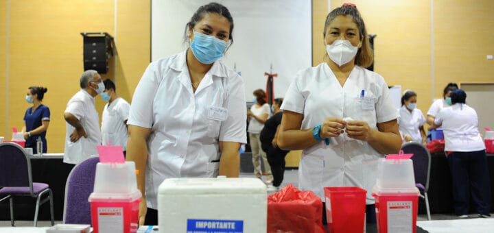 alt="dos vacunadoras con contenedores para vacunas"