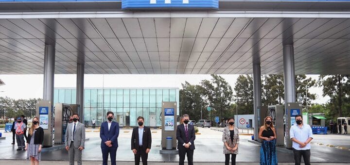 alt="varias personas posan en el frente de una estación de servicios de YPF"