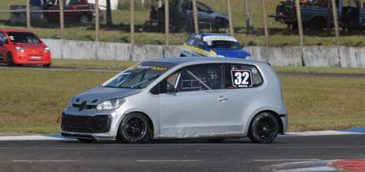 alt="un automóvil de color gris corriendo en la pista del autódromo de Concordia, detrás puede observarse un automóvil pintado de varios colores y un muro con alambrado"
