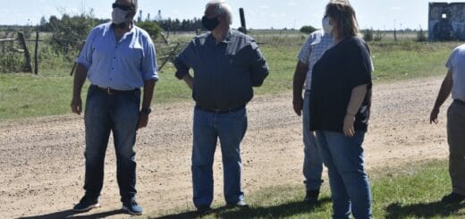 alt_="cuatro hombres recorren un sector donde hay un camino de tierra y se puede observar la señalización de un cruce ferroviario"