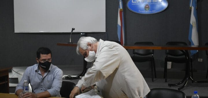 alt="en la fotografía, dos hombres abren los sobres con ofertas para una licitación"