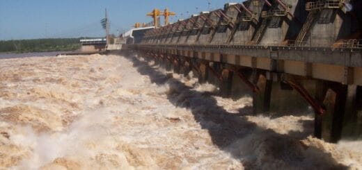 alt="en la imagen, una represa con los vertederos abiertos y el agua saliendo con gran velocidad y fuerza"