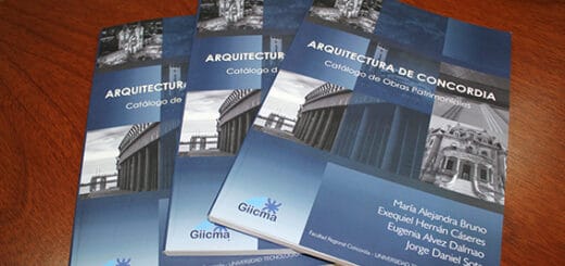 alt="sobre una superficie que puede ser madera, tres ejemplares del libro sobre el patrimonio arquitectónico de Concordia"