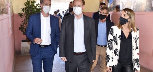 alt="en la fotografía puede haber dos hombres y una mujer caminando juntos por un pasillo, detrás se puede ver a otras personas"