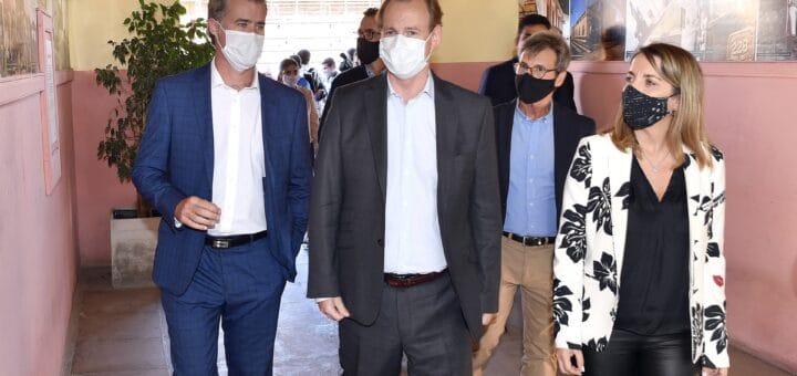 alt="en la fotografía puede haber dos hombres y una mujer caminando juntos por un pasillo, detrás se puede ver a otras personas"