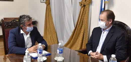 ; alt="a la izquierda en la fotografía, el intendente de Federación Ricardo Bravo; a la derecha, el gobernador Gustavo Bordet; los dos están sentados mesa de por medio, sobre la mesa hay envases de agua mineral; detrás de ambos, varios cuadros, cortinas y una bandera"