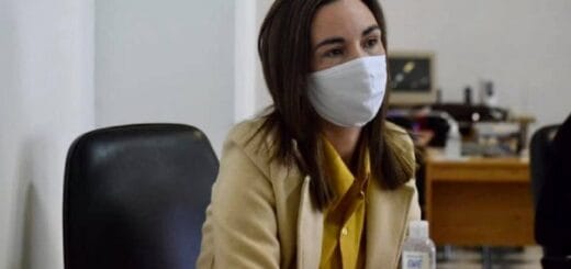 alt="mujer sentada tras un escritorio, con un barbijo"