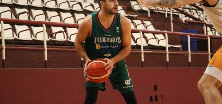 alt="en primer plano, un jugador de básquet con la pelota en sus manos, detrás una tribuna vacía"