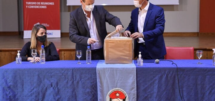 alt="en la fotografía puede verse a dos hombres con barbijo abriendo una caja, a la izquierda y sentada está una mujer"