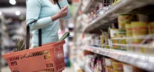 alt="una mujer realiza compras en la góndola de un supermercado"