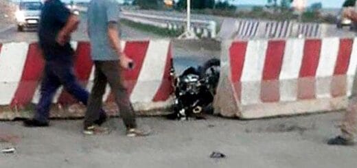 alt="motocicleta incrustrada entre dos bloques de cemento, dos personas están en las proximidades"