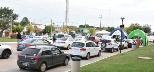 alt="larga fila de vehículos que transportan gente que no camina y quiere ser vacunda"
