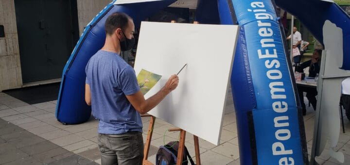 alt="artista plástico pinta un cuadro en un lienzo, ante un gazebo desmontable ubicado en la peatonal de concordia"