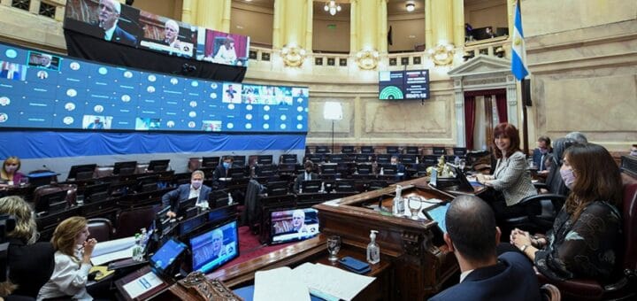 alt="en la fotografía, el recinto de la cámara de senadores, semivacío, con algunos senadores"